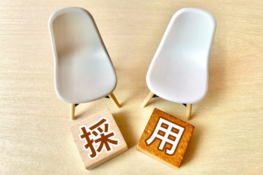白い椅子と採用と書かれた正方形の木の板
